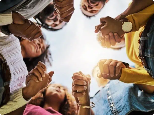 A diverse group of individuals forming a circle, holding hands together in unity and solidarity